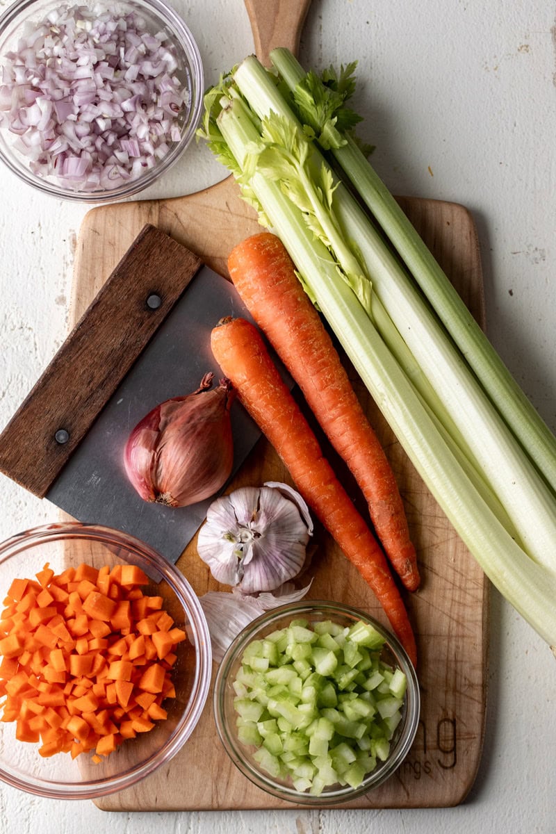 mirepoix ingredients carrots celery and onion on cutting board.