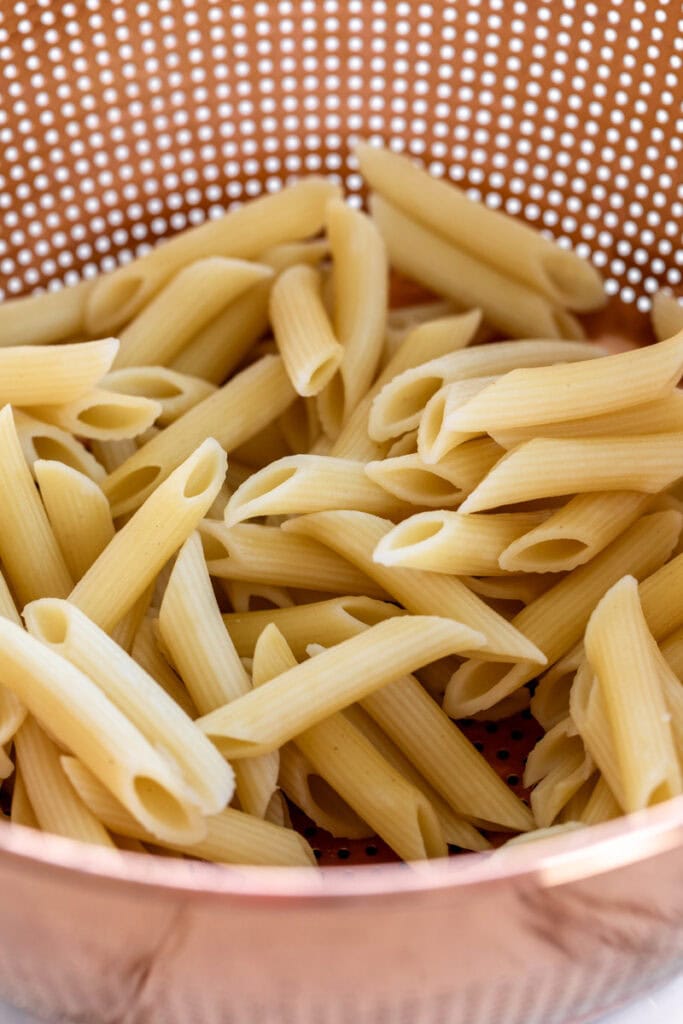 par boiled penne pasta in strainer.