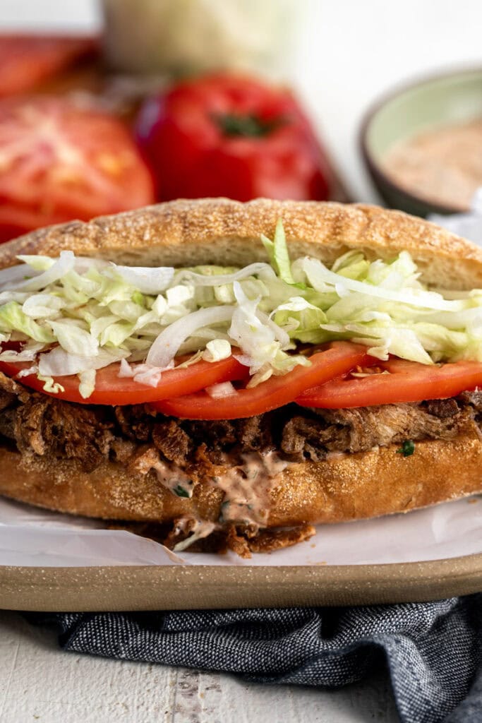 Crispy oyster mushroom Po\' Boy with shredded lettuce and sliced tomato with remoulade sauce.