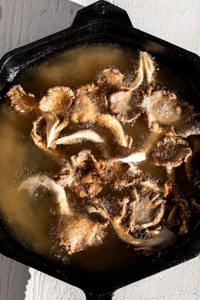fried oyster mushrooms in cast iron pan with oil.
