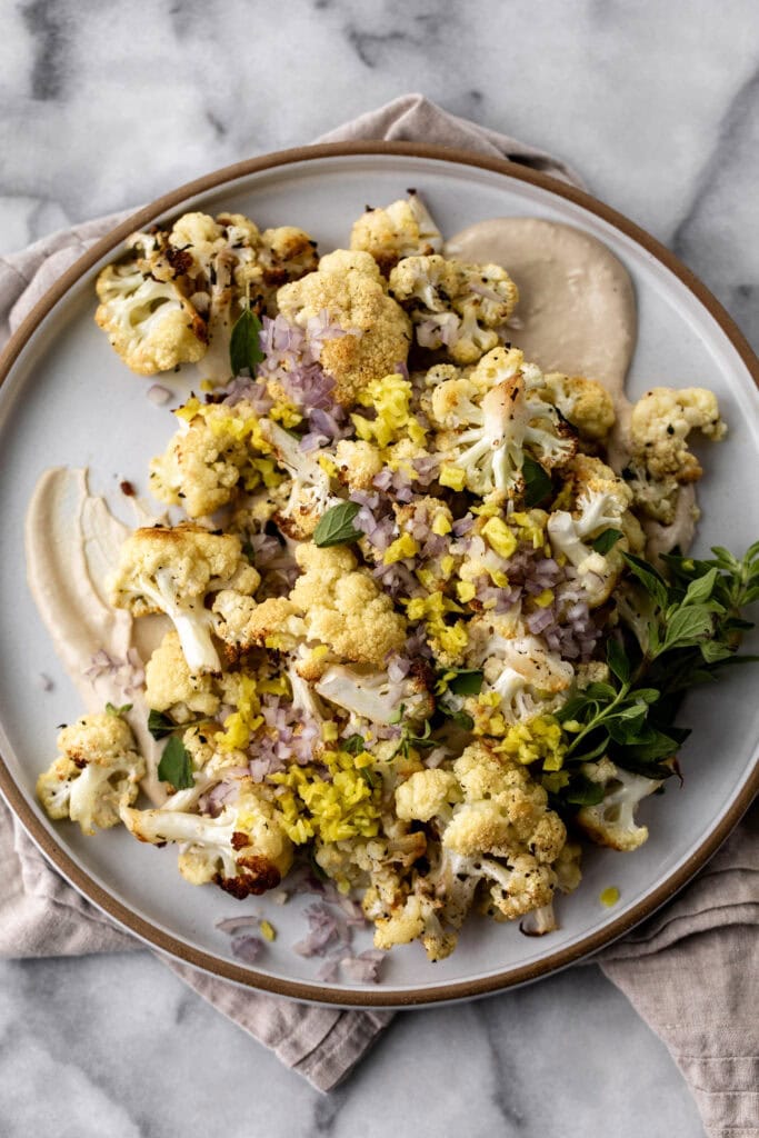 Roasted Cauliflower with Tahini recipe topped with pepperoncini and shallots.