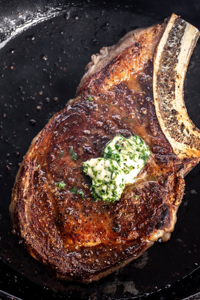 seared bone-in ribeye steak with garlic herb compound butter.