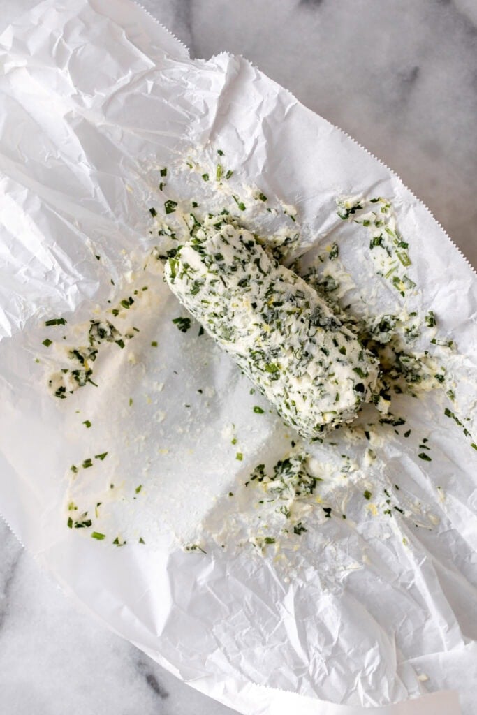 garlic and herb compound butter rolled out in parchment paper.