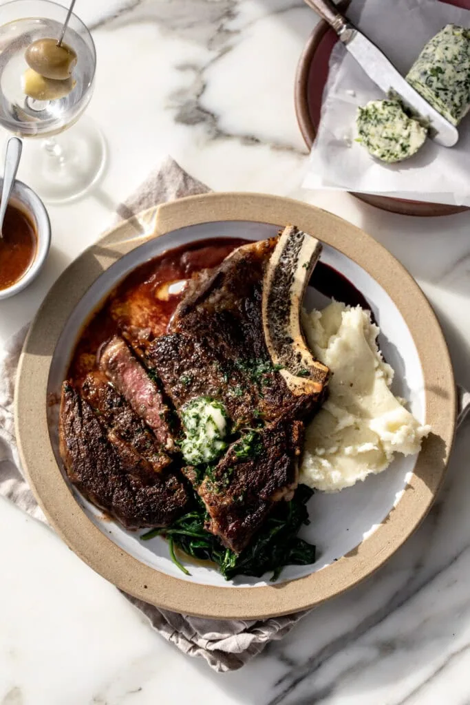 Seared steak with red wine reduction and garlic compound butter over mashed potatoes.