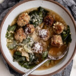 Italian wedding soup with chicken bone broth and escarole garnished with parmesan cheese.