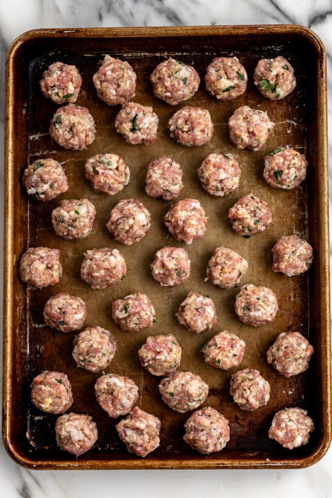 mini pork meatballs rolled on baking sheet.