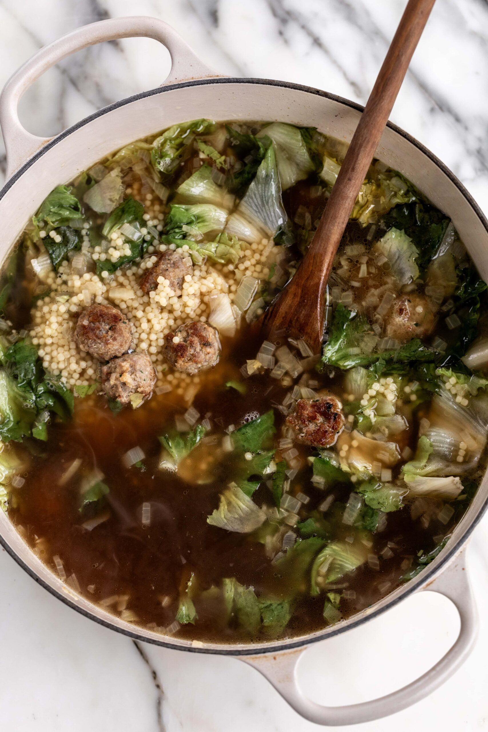 Italian wedding soup with chicken bone broth in pot.