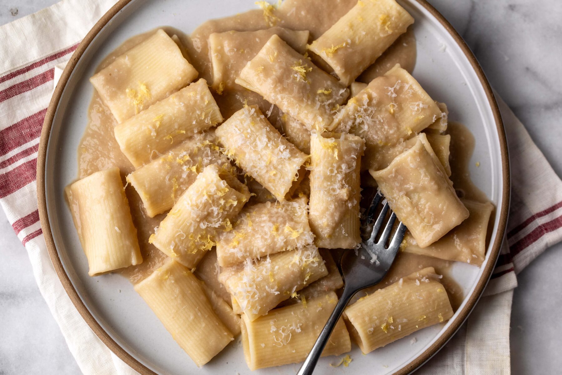 Simple creamy white bean and lemon pasta made with Paccheri noodles on plate.
