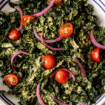 simple shredded kale salad with nutritional yeast with pickled red onion and cherry tomatoes.