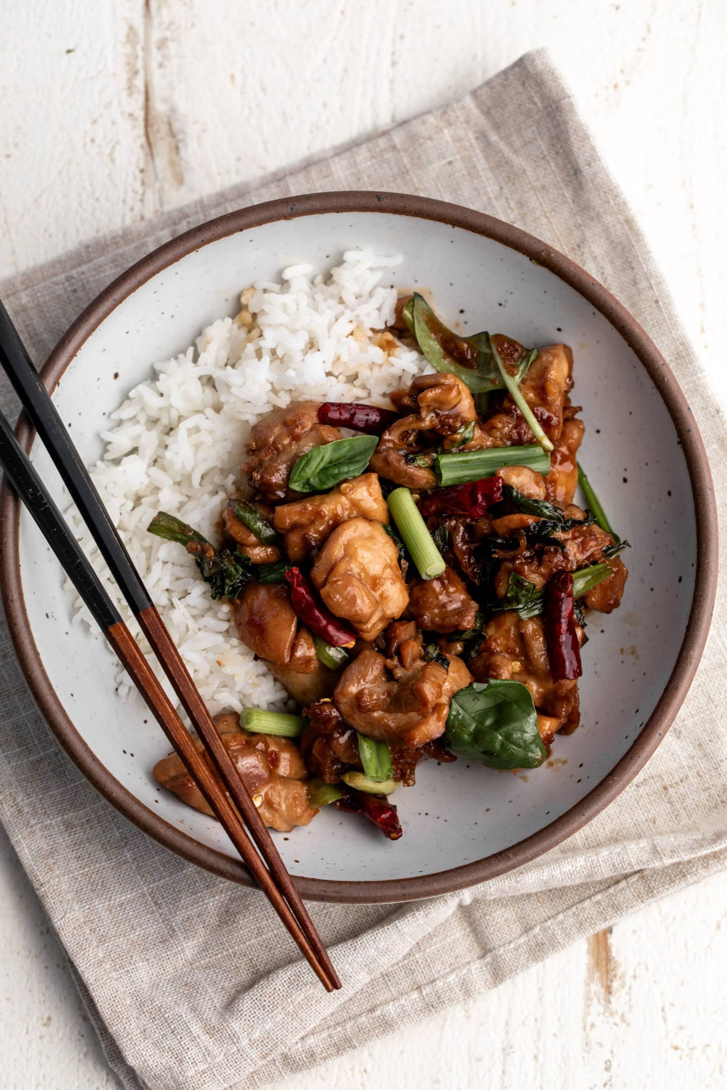 taiwanese three cup chicken in stone bowl with chopsticks.