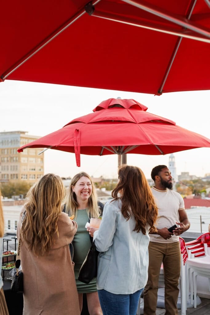 women talking under red umbrella. 