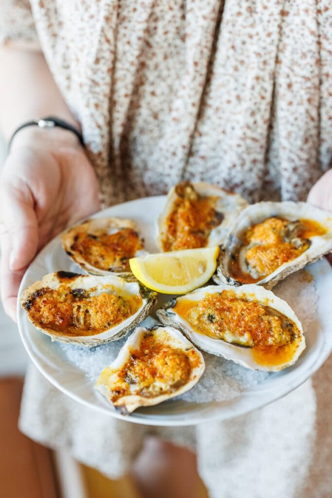 char broiled oysters on plate garnished with lemon wedge.