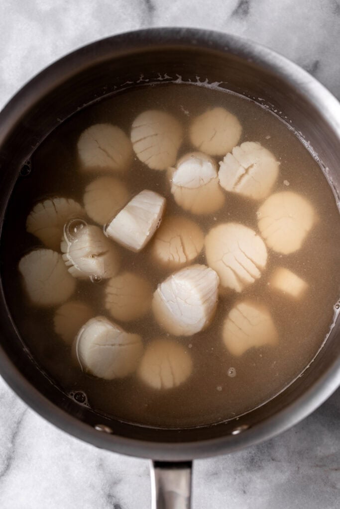 poached scallops in poaching liquid.