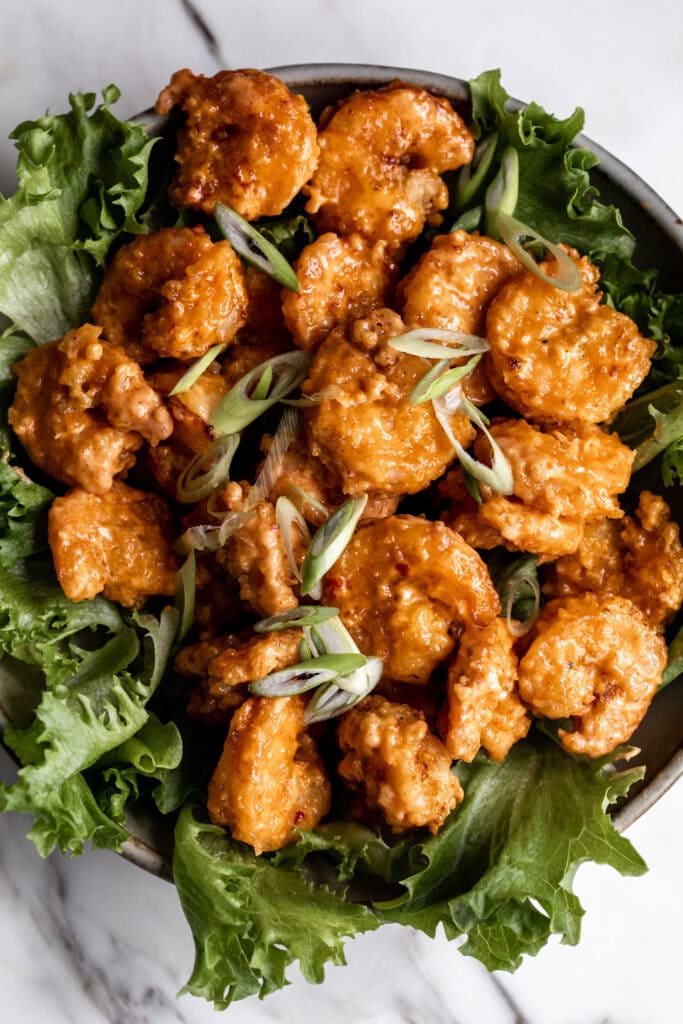 creamy bang bang shrimp over green lettuce.