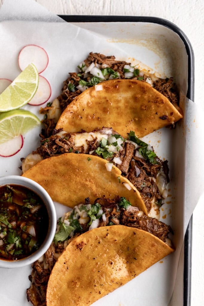 authentic birria tacos with cilantro and onion salsa on corn tortillas.