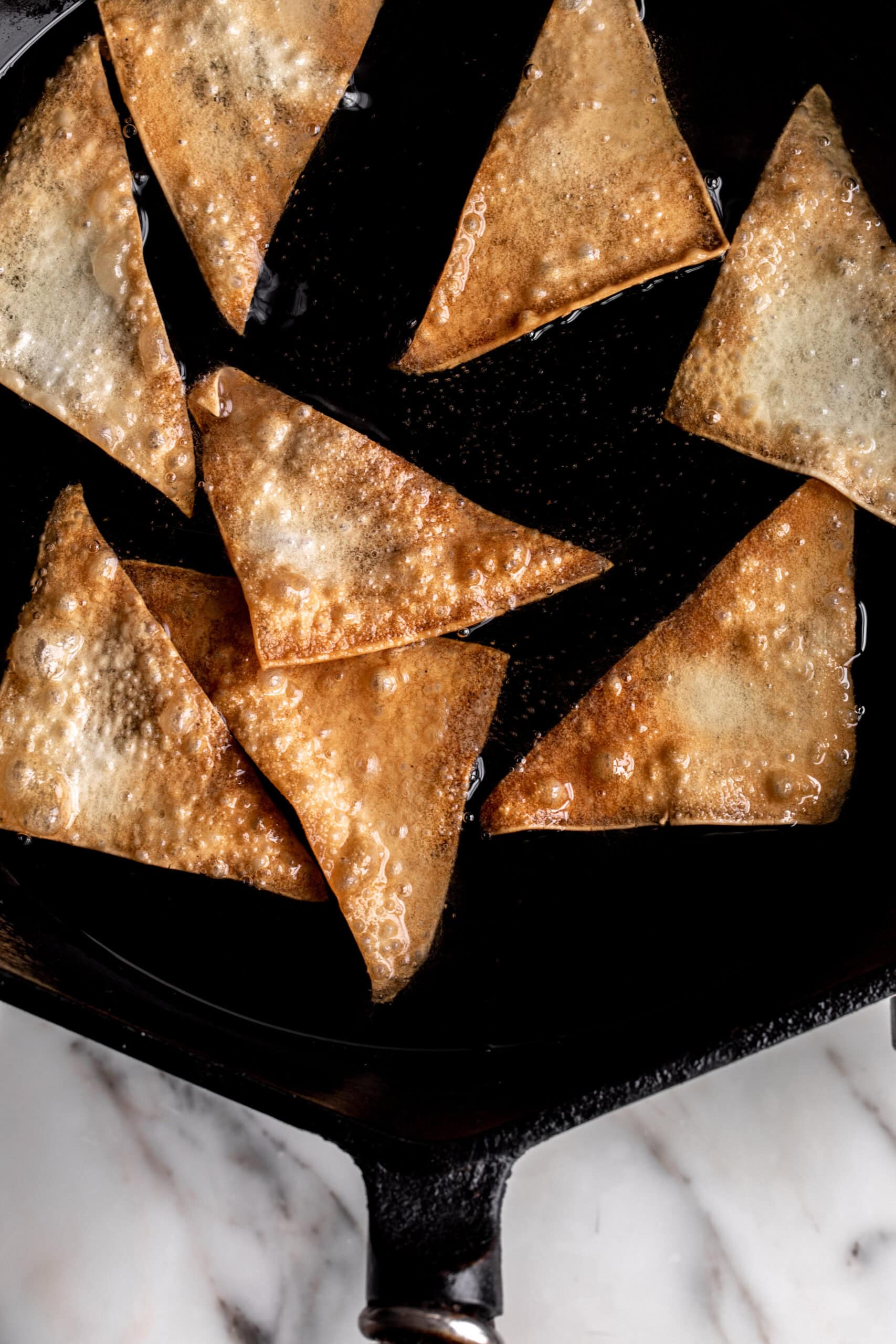 fried wontons in oil in cast iron pan.