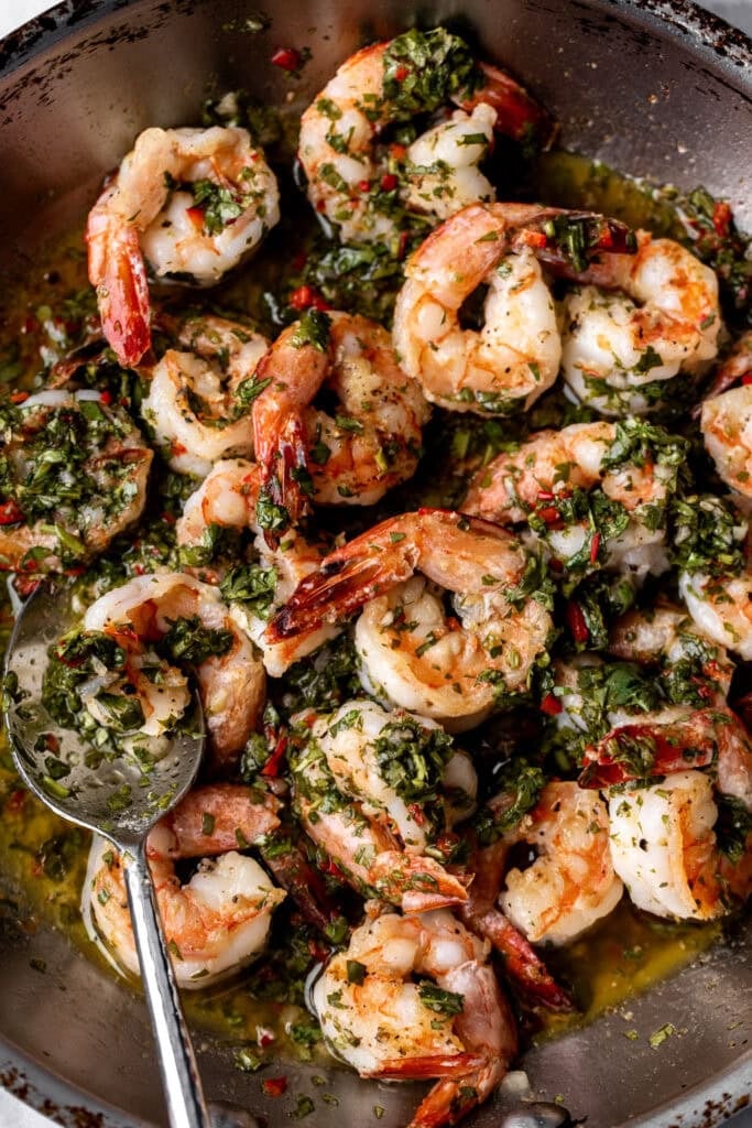 chimichurri shrimp in sauté pan with spoon.