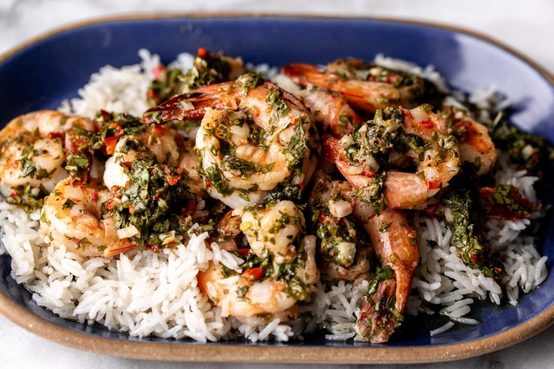 chimichurri shrimp over coconut rice on blue stoneware plate.
