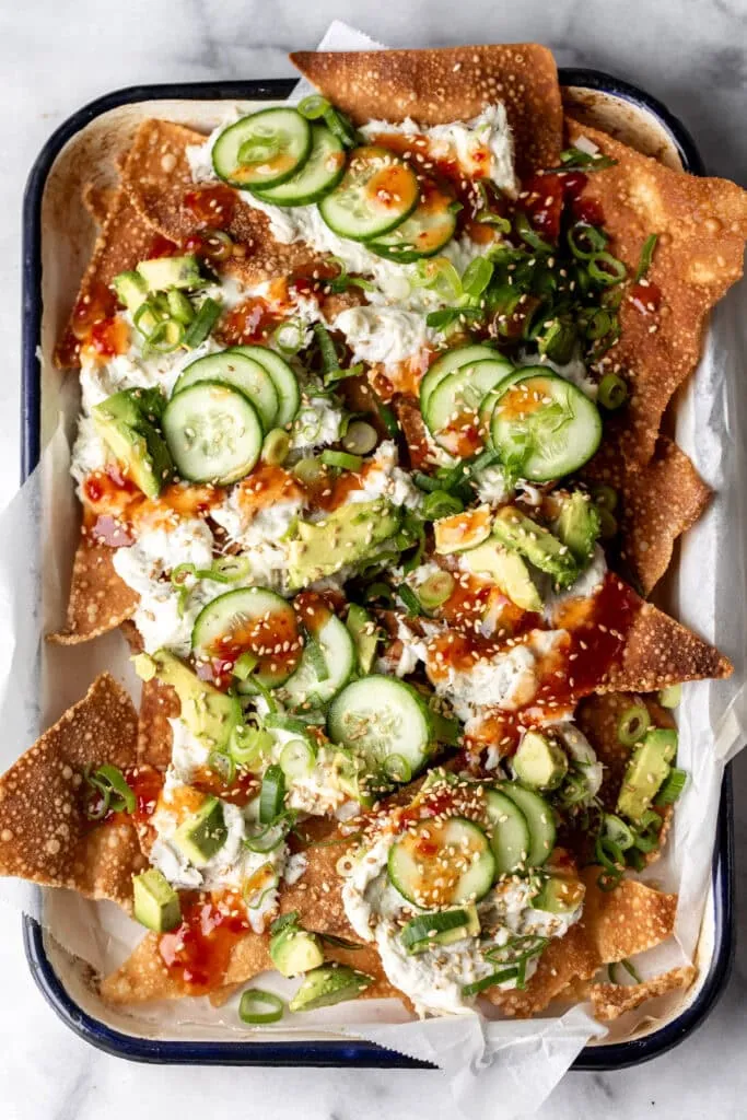 crab rangoon wonton nachos with cream cheese and sweet chili sauce on enamel tray.