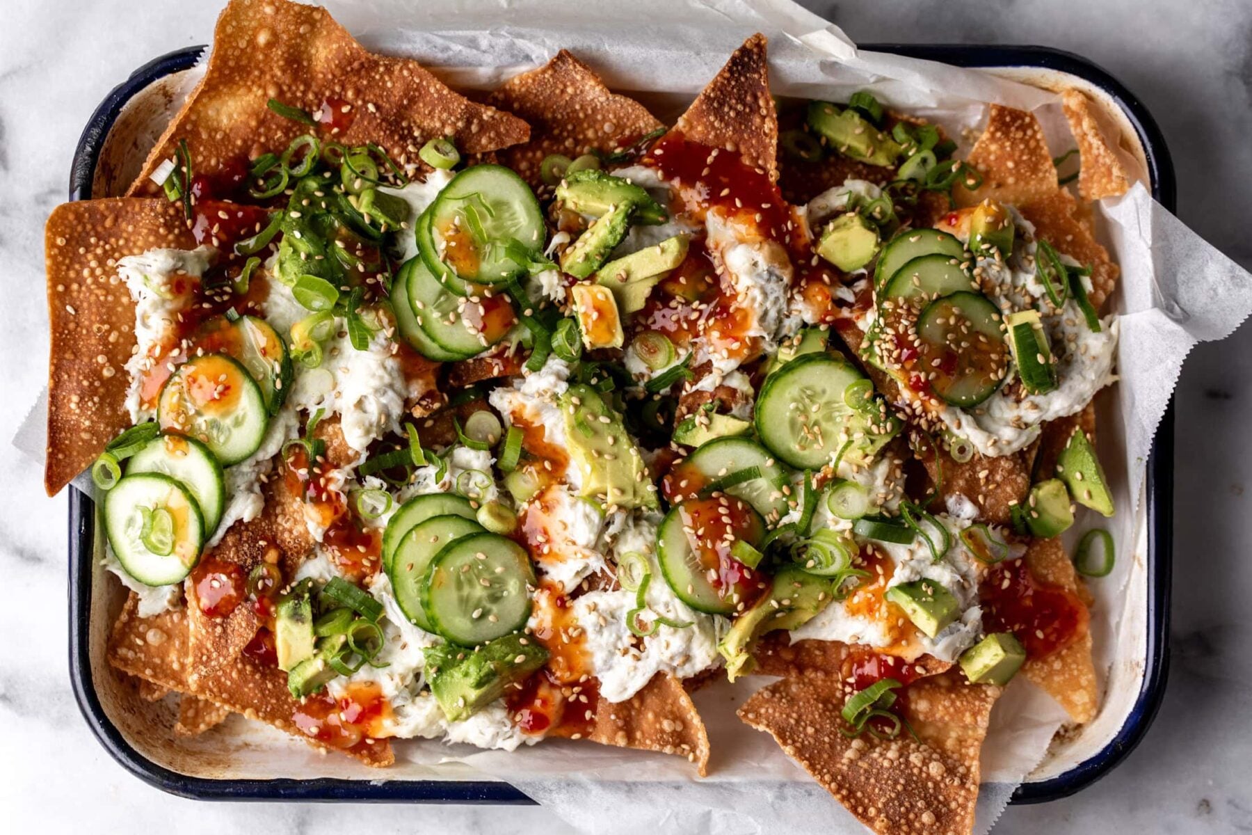 crab rangoon wonton nachos with cream cheese and sweet chili sauce on enamel tray.