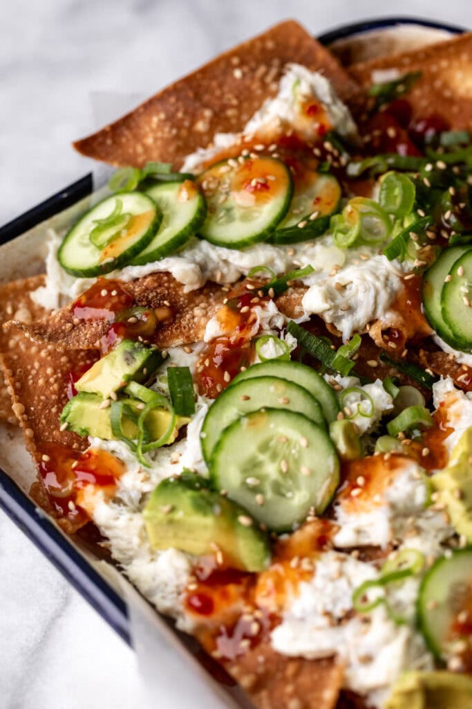 crab rangoon nachos with sweet chili sauce, avocado and cucumber slices.