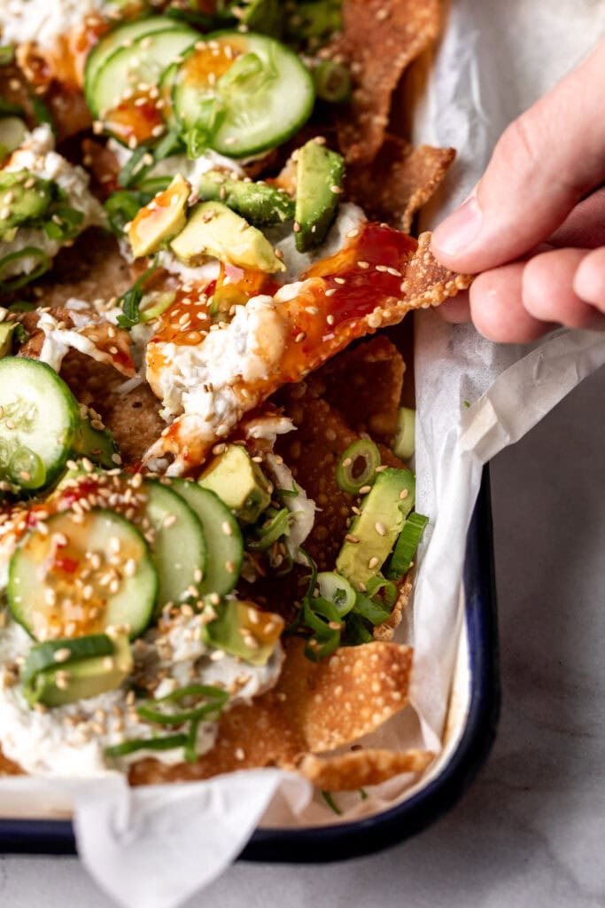 hand picking up crab rangoon wonton nacho from tray.
