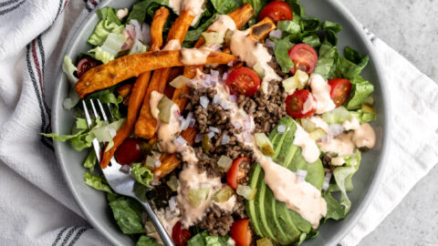 deconstructed loaded burger bowl with ground beef, sweet potato fries and avocado.