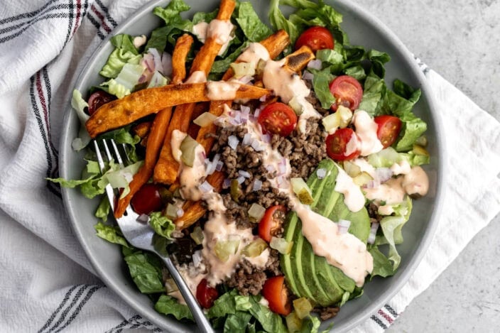 deconstructed loaded burger bowl with ground beef, sweet potato fries and avocado.