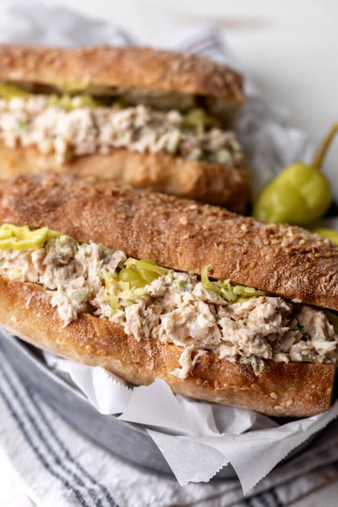 lemony tuna salad sandwich with pepperoncini on parchment paper.