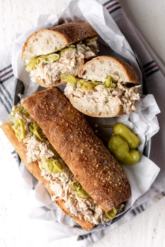 lemony tuna salad sandwich with pepperoncini on parchment paper overhead photo.