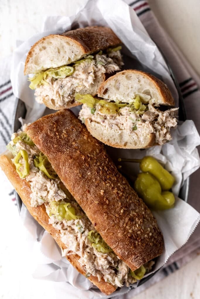 lemony tuna salad sandwich cut in half with pepperoncini.