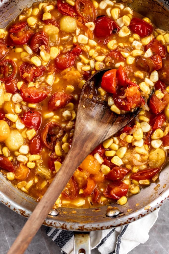 cherry tomatoes sautéed in pan with corn kernels.