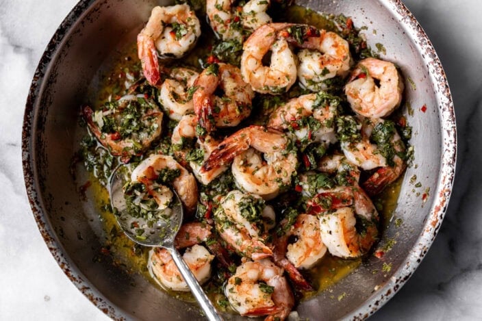 sautéed shrimp in pan with homemade chimichurri sauce.