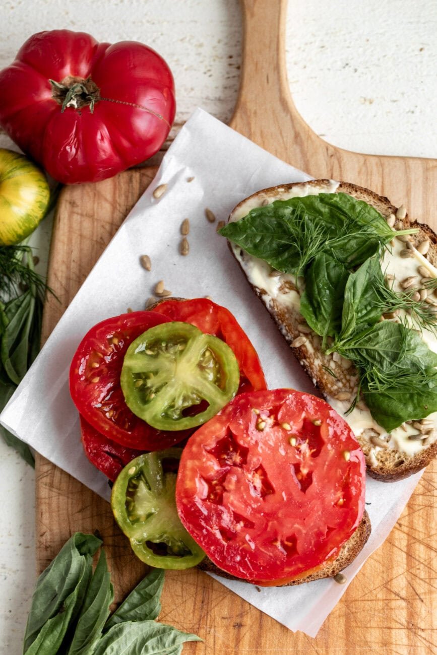 assembled tomato sandwich halves with herbs.
