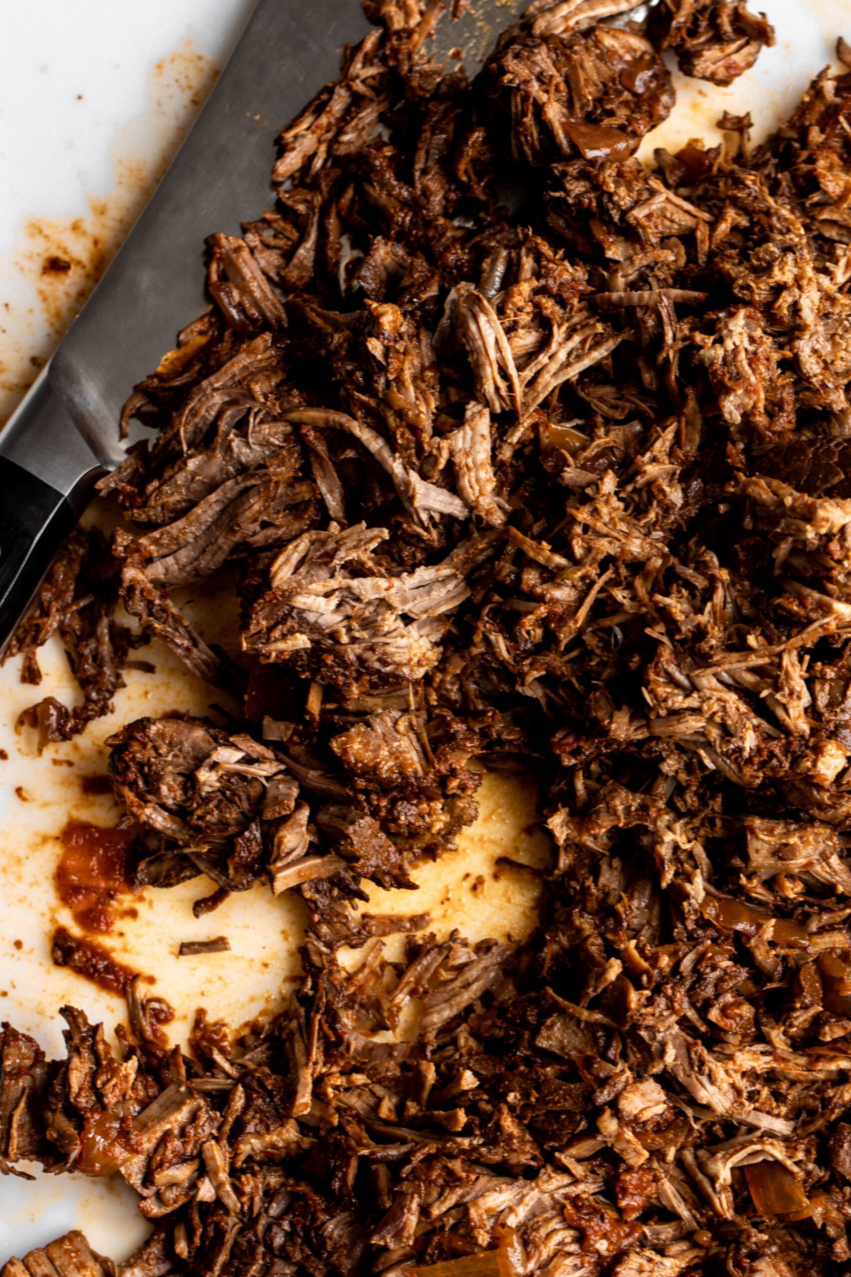 shredded braised beef on cutting board.