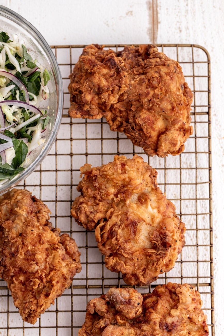 fried chicken thighs on wire rack.