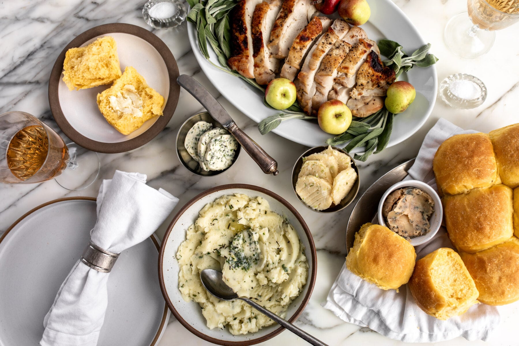 garlic herb butter, miso scallion butter and brown butter sage butter in dishes on thanksgiving table.