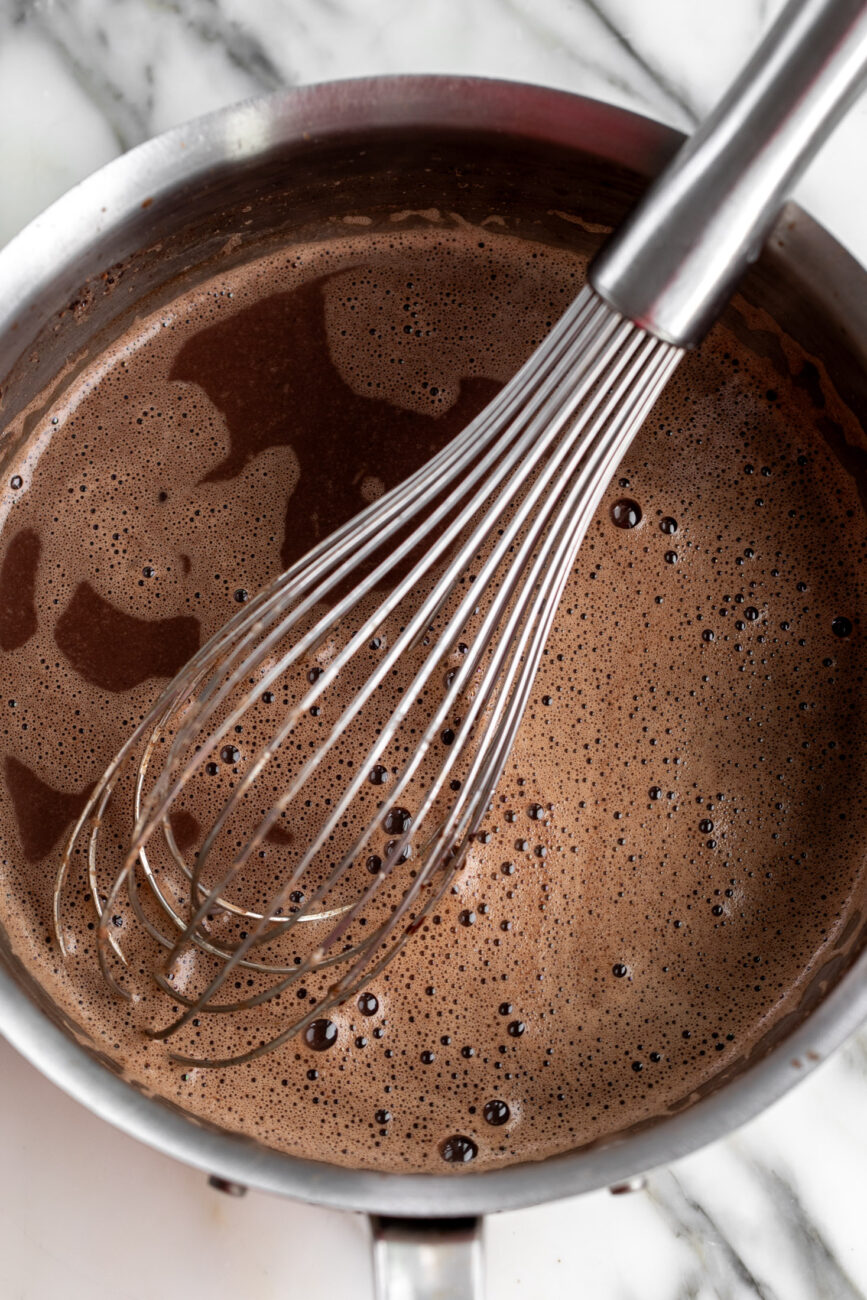 simmered hot chocolate in pot with whisk.