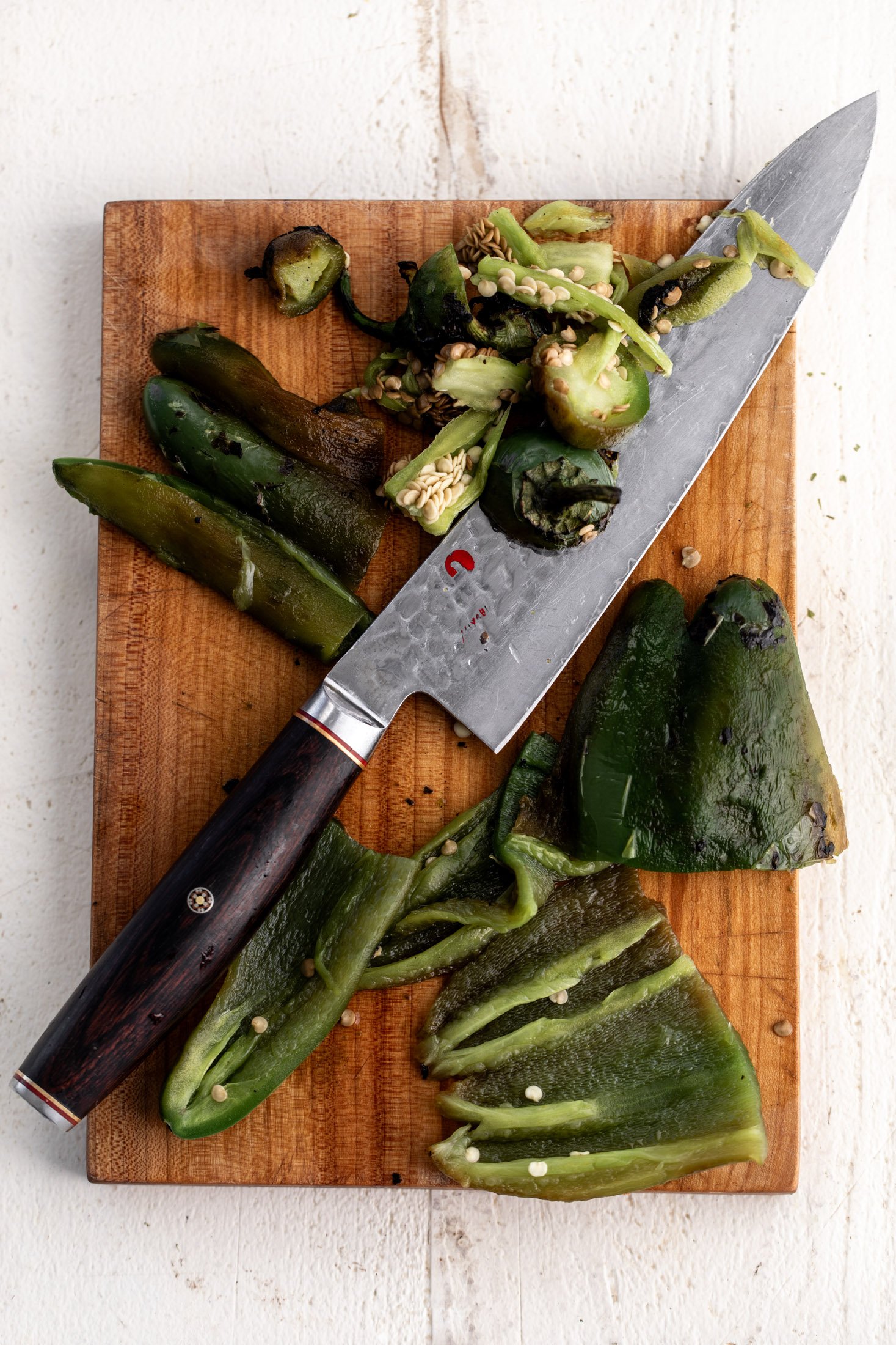roasted jalapeños chopped on cutting board.