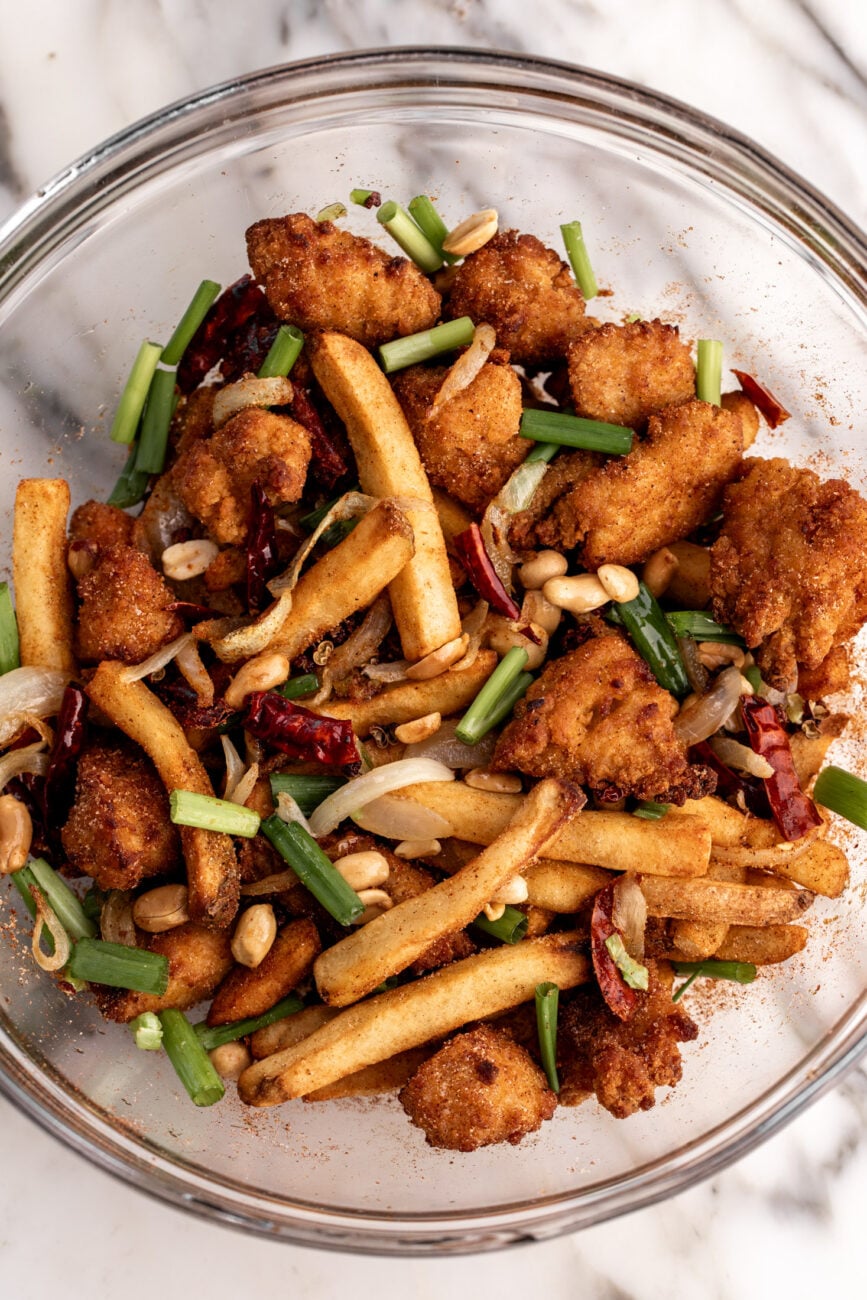 mixing bowl filled with irish spice bag ingredients chicken nuggets and french fries.