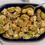 white wine-braised leeks with crispy buttered breadcrumbs with serving spoon.