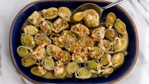 white wine-braised leeks with crispy buttered breadcrumbs with serving spoon.