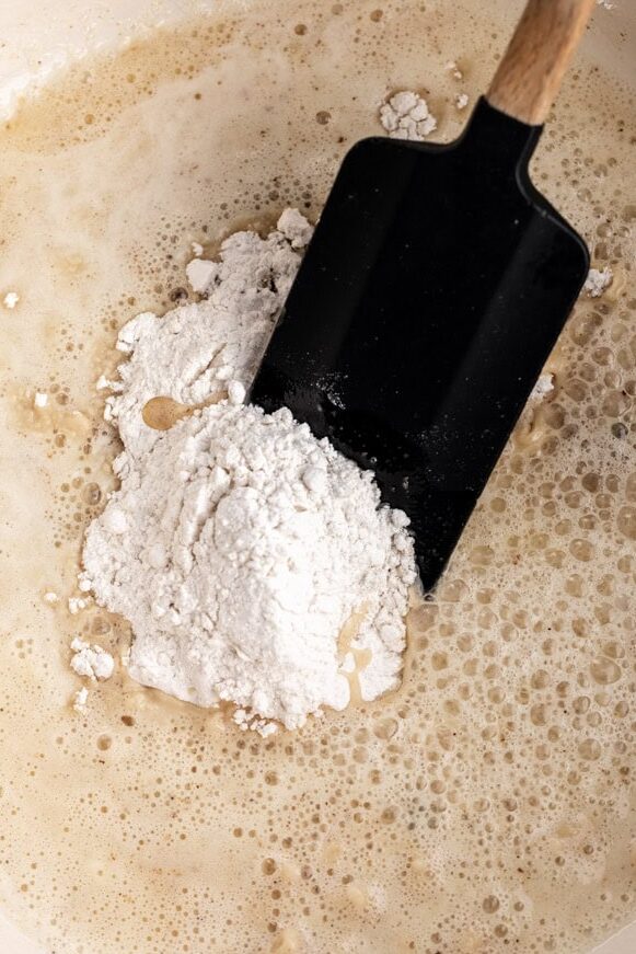 Adding flour to pot to create a roux.