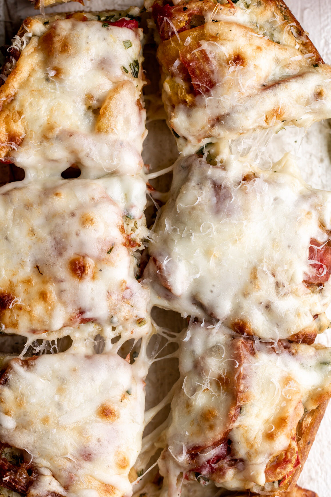 cheesy bread with heirloom tomato with garlic butter and mozzarella cut into portions.