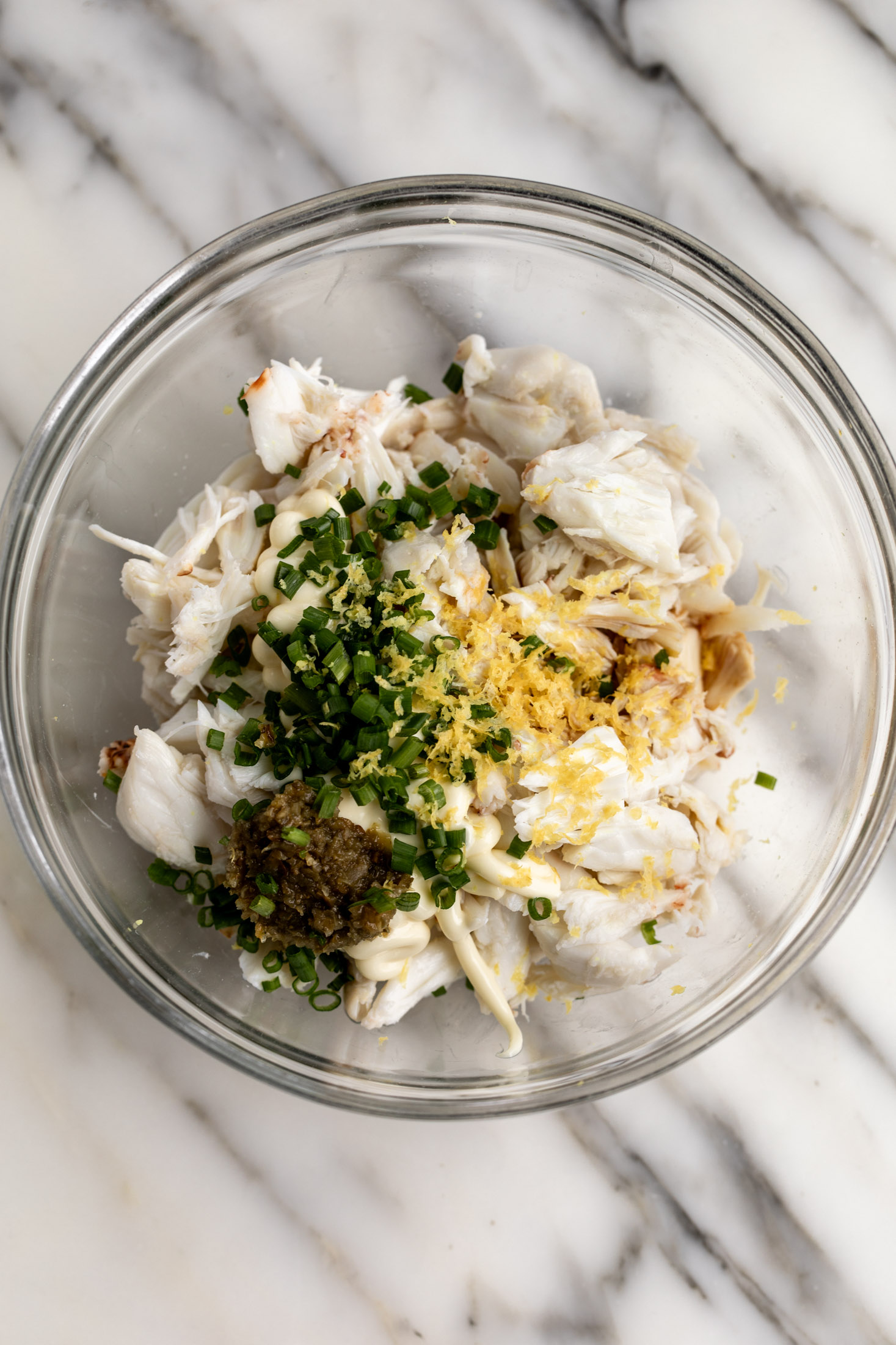 spicy creamy crab topping with chives and lemon in mixing bowl.