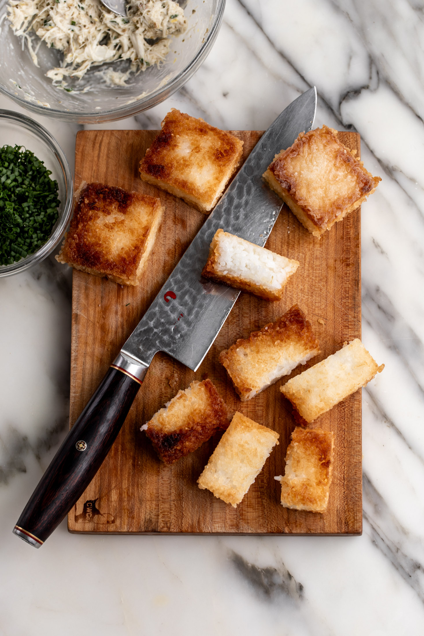 halved squares of crispy rice on cutting board with knife.