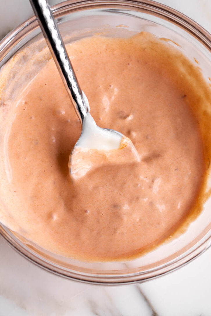 creamy hot sauce stirred in glass bowl.