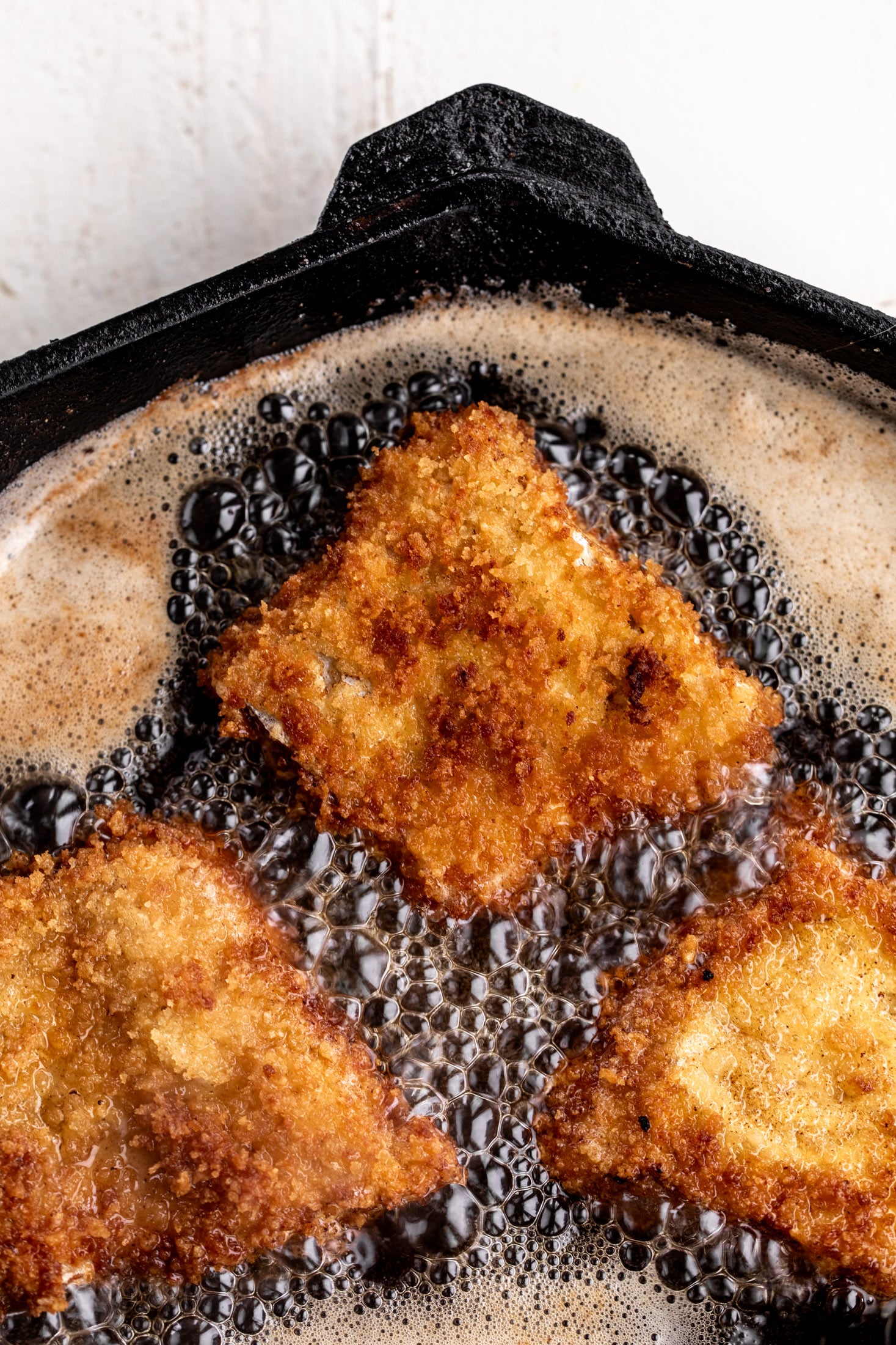 fried filet of fish in cast iron pan.