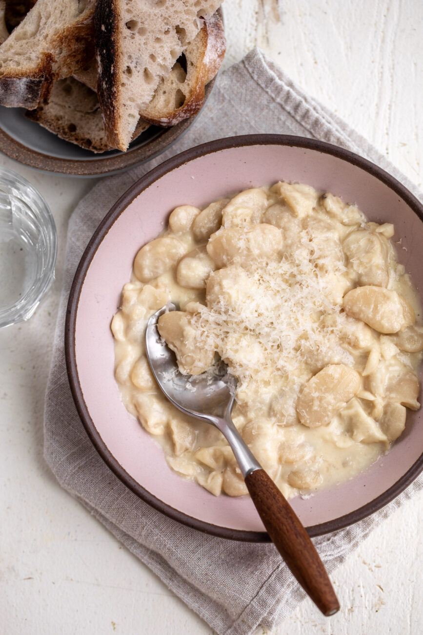 10-minute Alfredo butter beans garnished with parmesan cheese with a side of bread.