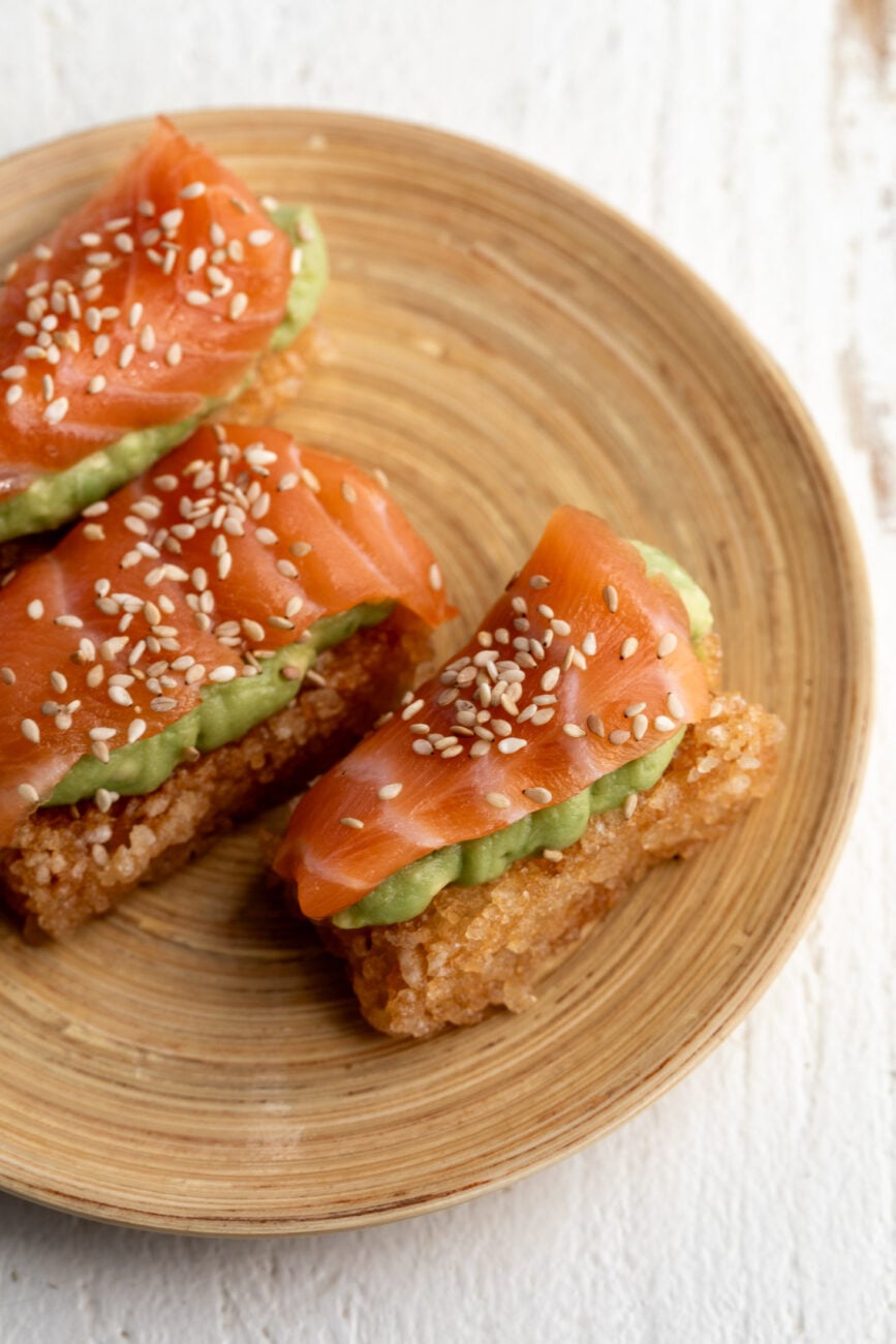 crispy rice with salmon and avocado garnished with sesame seeds.